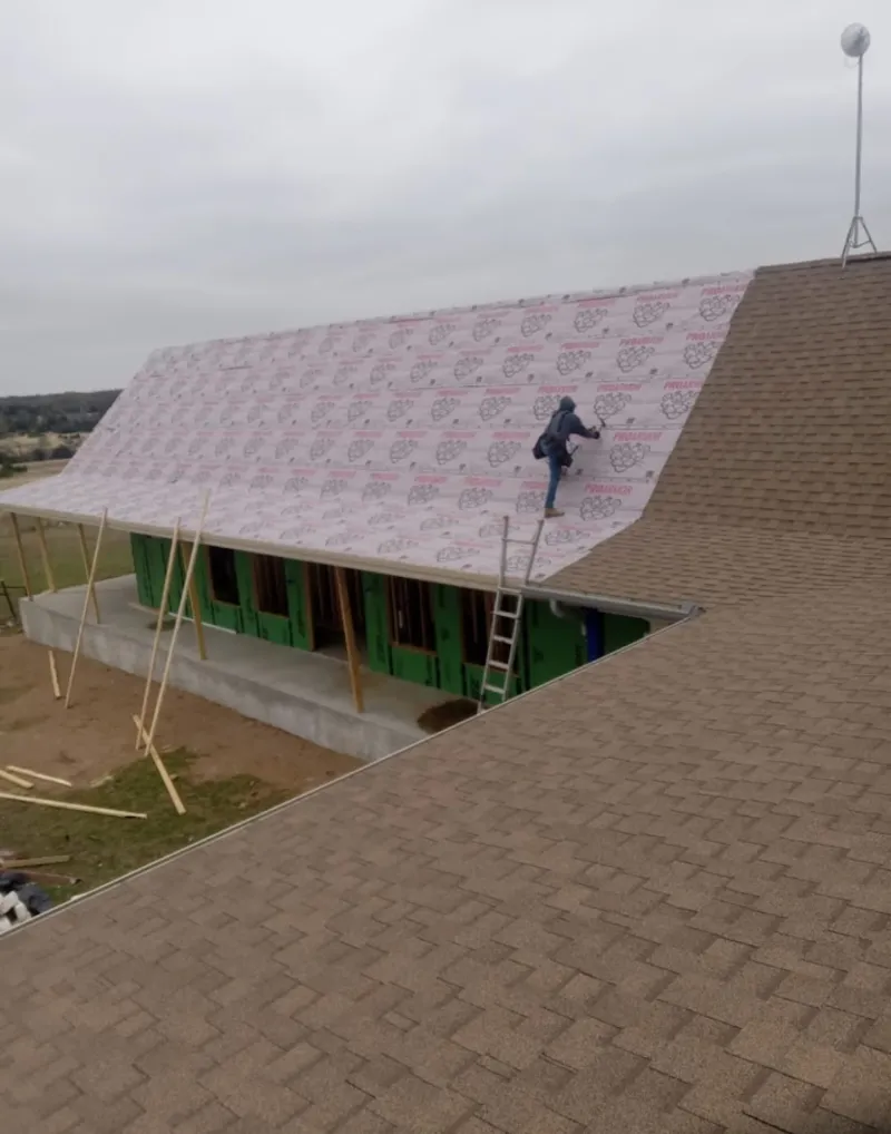 Worker preparing underlayment for a metal roof installation in Lilburn